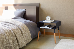 Front view of black Storage Table displaying clock, phone, and books in bedroom by Yamazaki Home. view 23