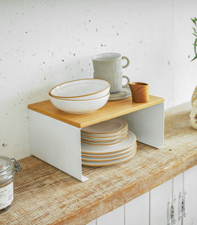 Side view of single white Stackable Countertop Shelf displaying cups and plates on kitchen shelf by Yamazaki Home. view 8