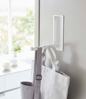 Close up of white Yamazaki Home Magnet Folding Hanger open with multiple tote bags hung view 6