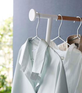 Close up of clothes hung on white Yamazaki Home Clothes Steaming Leaning Pole Hanger view 5