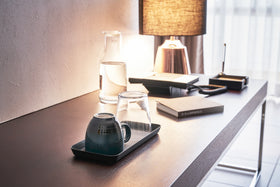 Black Accessory Tray holding mug and glass on desk by Yamazaki Home. view 21