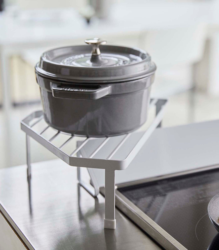 View 4 - Side view of White Corner Riser holding pot next to kitchen stovetop by Yamazaki Home.