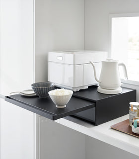 Countertop Drawer with Pull-Out Shelf by Yamazaki Home in black with the shelf pulled out, holding two bowls. Kitchen appliances are on top of the unit. view 16