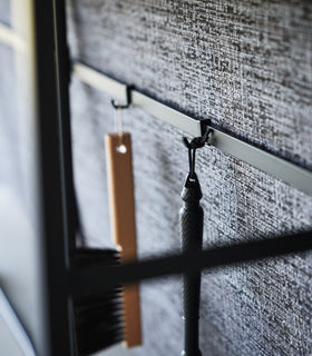Image showing items hanging form hooks on the back bar of the Long Console Table by Yamazaki Home in black. view 14