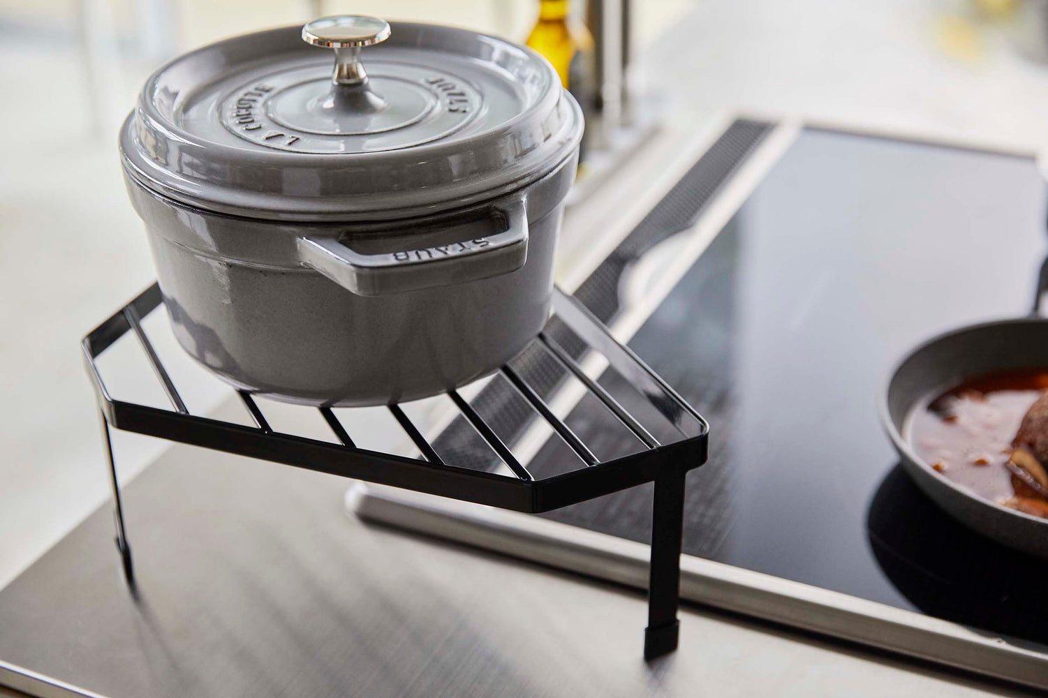 View 11 - Side view of Black Corner Riser holding pot next to stovetop by Yamazaki Home.