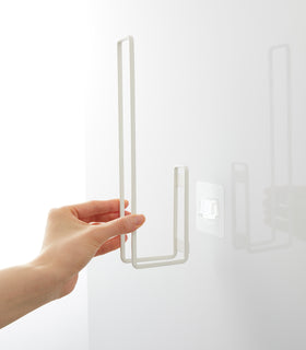 Attaching a white Yamazaki Home Traceless Adhesive Toilet Paper Holder to the adhesive hook view 8