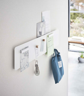 Side view of a Yamazaki white Magnetic Wall Panel with keys and a bag hanging from hooks view 3