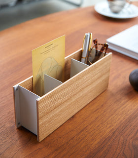 Close up view of ash Organizer Caddy containing pen and glasses on table by Yamazaki Home. view 4