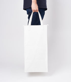 Side view of a person holding the liner of the small Laundry Hamper with Cotton Liner in white by Yamazaki Home by the handles. view 4