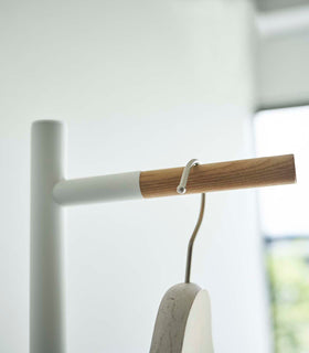 Close up of the top of a white Yamazaki Coat Rack with a coat hanger on it view 5