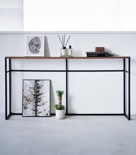 Straight view of the Long Console Table by Yamazaki Home in black with decorative items. view 15