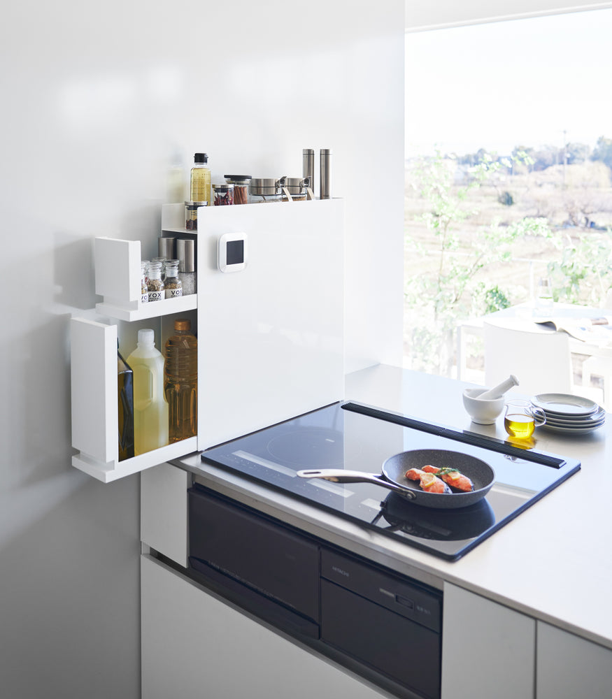 View 2 - White Yamazaki Home Two-Tier Sliding Drawer Seasoning Rack with both tiers opened next to a stove top