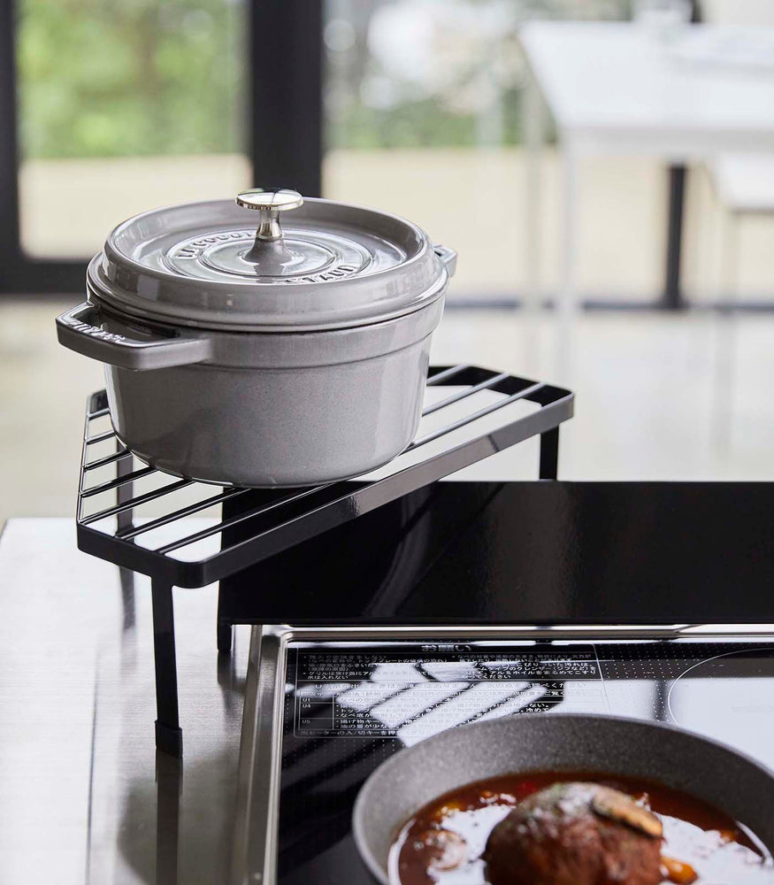 View 9 - Black Corner Riser holding pot next to stovetop by Yamazaki Home.