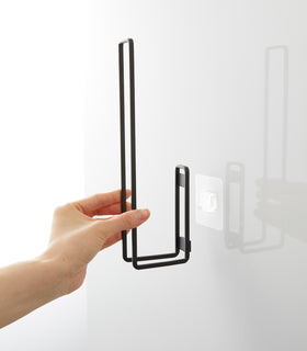 Attaching a black Yamazaki Home Traceless Adhesive Toilet Paper Holder to the adhesive hook view 16