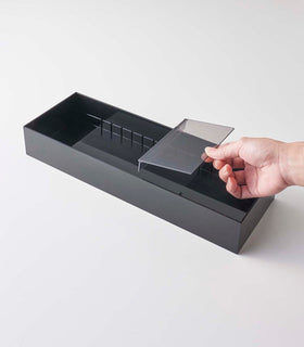 Person inserting dividers in black Cutlery Storage Organizer on white background by Yamazaki Home. view 13