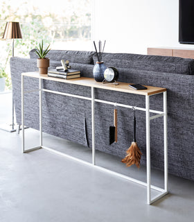 Diagonal view of the Long Console Table by Yamazaki Home in white placed behind a gray couch in a living room. view 2
