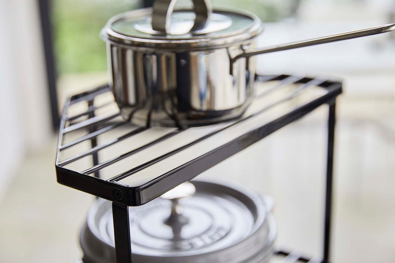 View 11 - Close up top view of Black Two-Tier Corner Riser holding saucepans by Yamazaki Home.