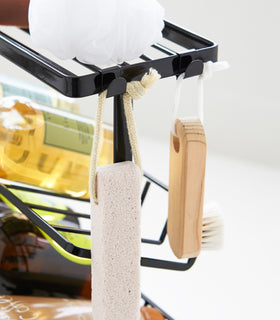 Close up view of black Freestanding Shower Caddy hooks holding beauty items by Yamazaki Home. view 15