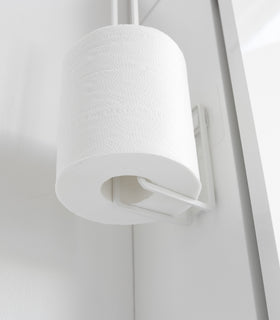 Close up of underside of white Yamazaki Home Traceless Adhesive Toilet Paper Holder with a roll stored view 6