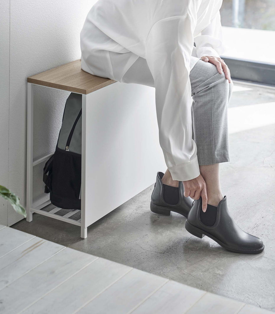 View 3 - Side view of white Yamazaki Discreet Entryway Storage Shelf sitting a model on it