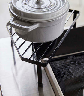 Black Corner Riser holding pot next to stovetop by Yamazaki Home. view 12