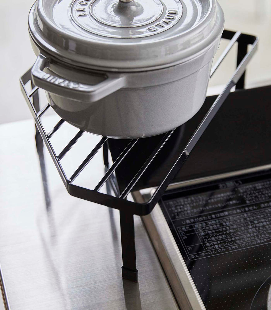 View 12 - Black Corner Riser holding pot next to stovetop by Yamazaki Home.