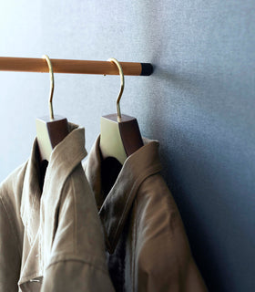 Close up of coats hung on black Yamazaki Home Clothes Steaming Leaning Pole Hanger view 14
