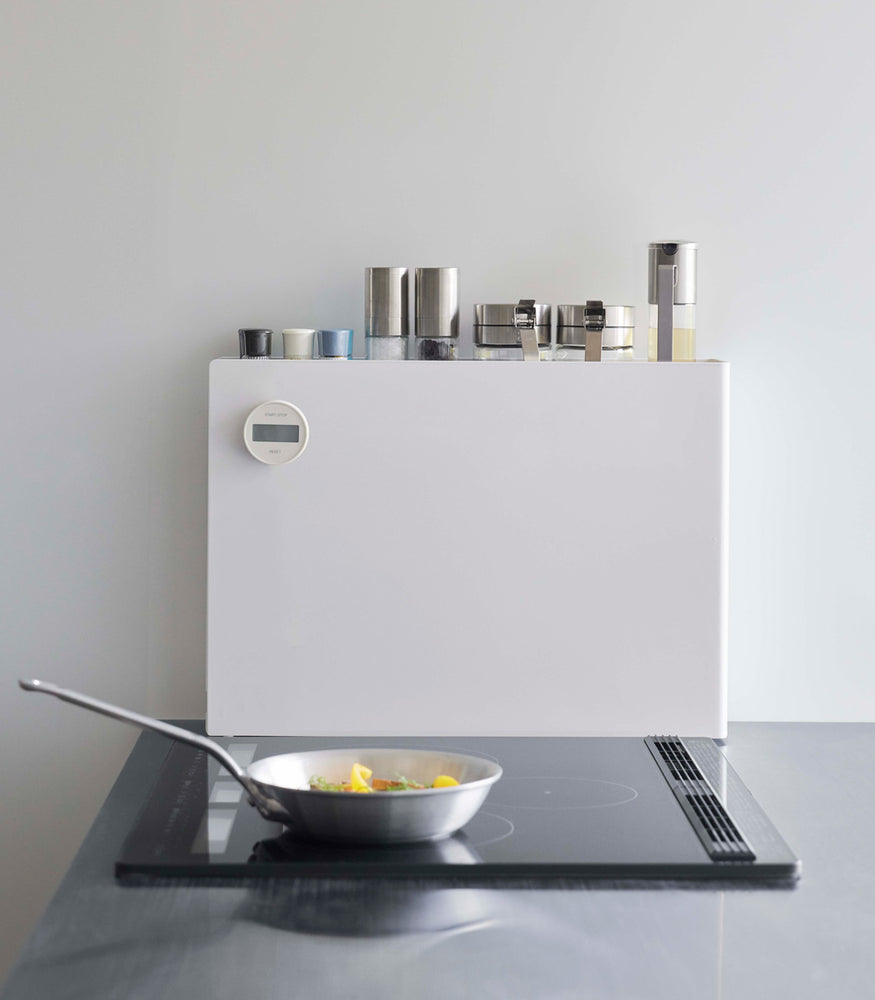 View 7 - White Yamazaki Home Sliding Seasoning Rack on a stove counter closed with spices stored