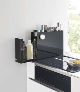 Black Yamazaki Home Sliding Seasoning Rack on a stove counter open view 9