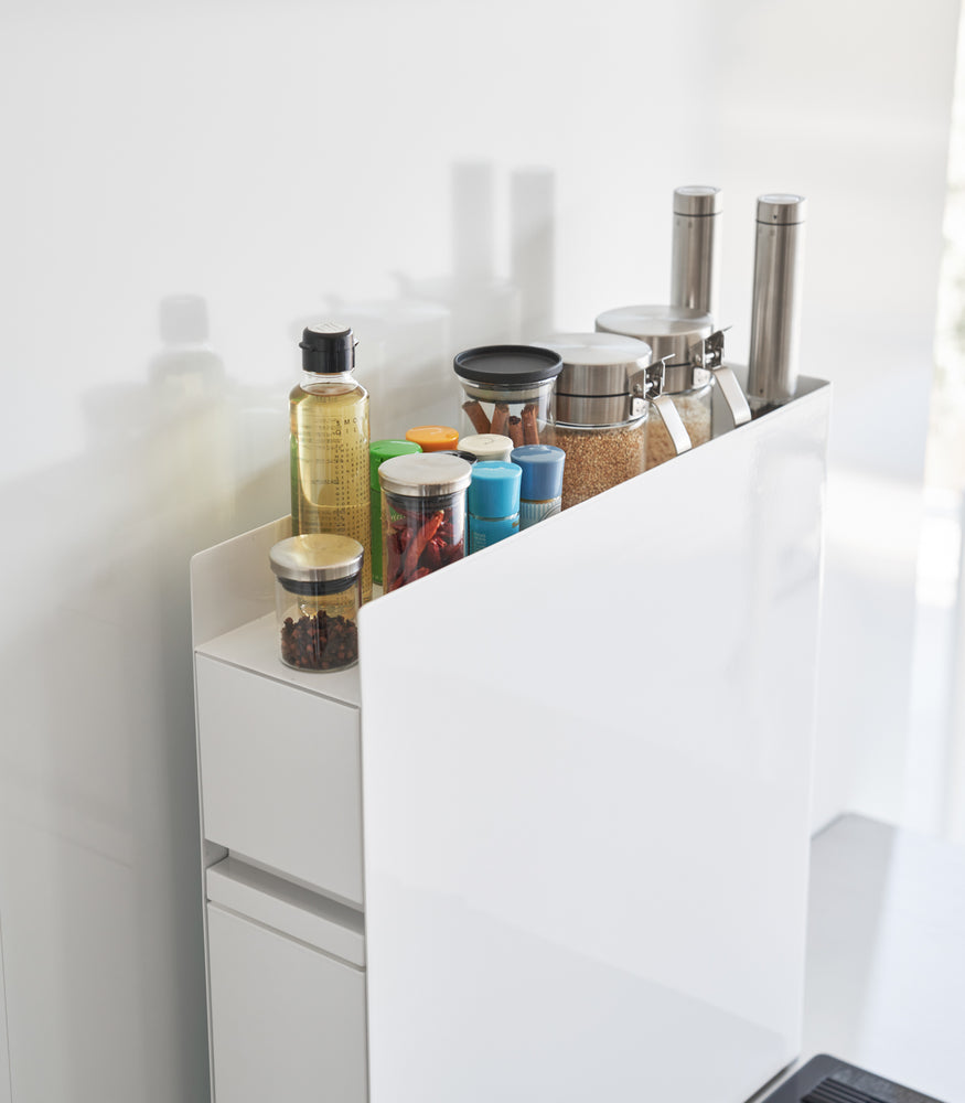 View 7 - Close up of top of white Yamazaki Home Two-Tier Sliding Drawer Seasoning Rack with spices stored on top