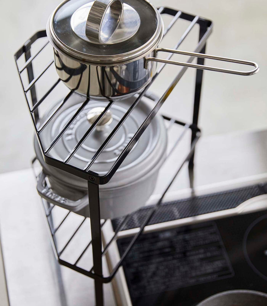 View 10 - Aerial view of Black Two-Tier Corner Riser holding pot and saucepan in kitchen by Yamazaki Home.