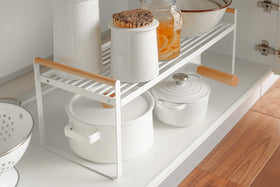 Front right diagonal view of white wired organizer rack holding pots, jars, and bowls. view 7