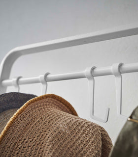 Close up of hats hung on hooks included with white Yamazaki Home Coat Rack with Hat Storage view 7