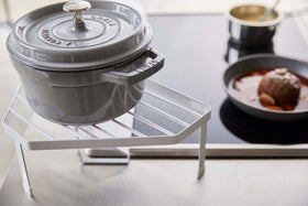 Close up view of White Corner Riser holding pot next to kitchen stovetop by Yamazaki Home. view 5