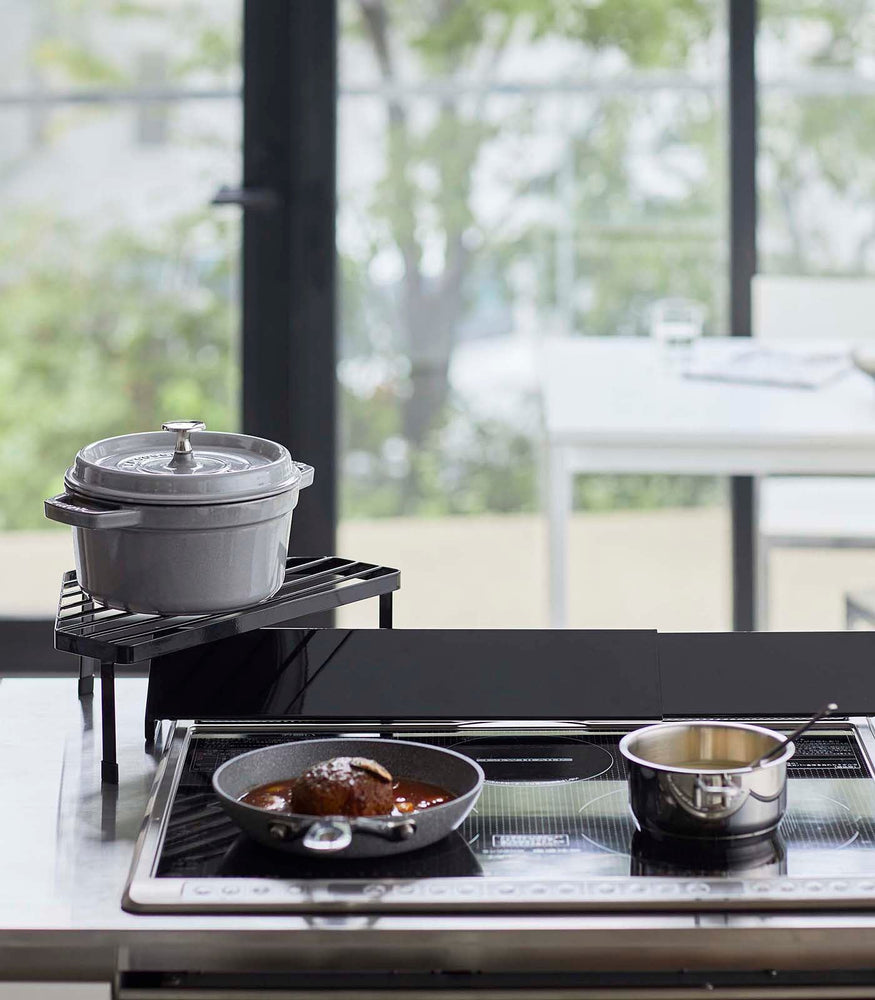 View 8 - Front view of Black Corner Riser holding pot next to kitchen stovetop by Yamazaki Home.