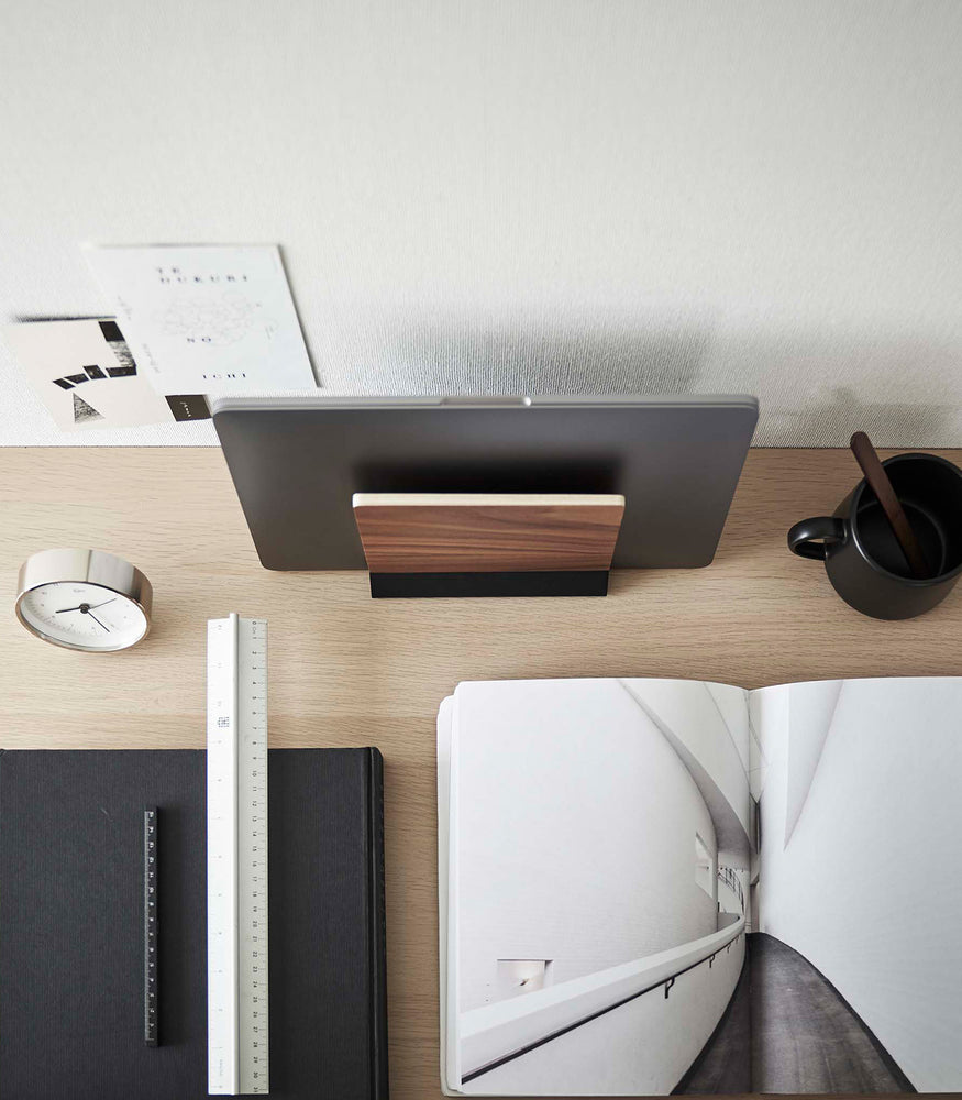 View 14 - A minimalist wooden laptop stand rests atop an organized desk, viewed from above.