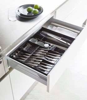 Black Expandable Cutlery Storage Organizer holding utensils in kitchen by Yamazaki Home. view 21