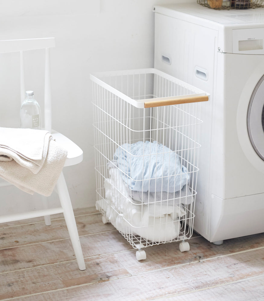 View 4 - Rolling Wire Basket holding clothes in laundry room by Yamazaki Home.