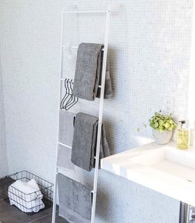 White Leaning Ladder Rack holding towels in bathroom by Yamazaki Home. view 4