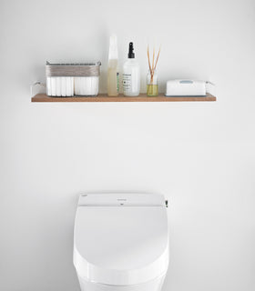 Front view of Wall-Mounted Shelf holding bathroom accessories in bathroom by Yamazaki Home. view 5