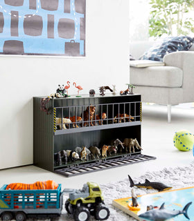 Dark green Two-Tier Toy Dinosaur and Animal Storage Rack in living room play area holding toy animals by Yamazaki Home. view 13