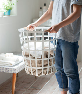 White Round Laundry Basket holding towels in laundry room by Yamazaki Home. view 4