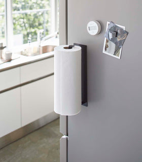 Black Magnetic Paper Towel Holder holding dish towel on kitchen fridge by Yamazaki Home. view 9