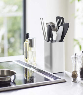 White Utensil Holder holding kitchen utensils on stove countertop by Yamazaki Home. view 2