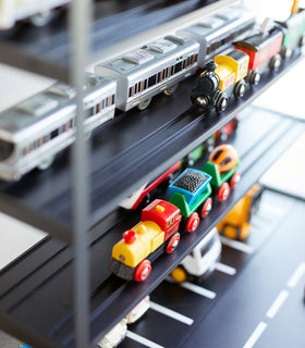 Close up view of black Kid's Parking Garage shelving holding toy trains by Yamazaki Home. view 13