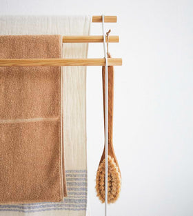Front view of Bath Towel Rack holding towels and brush on white background by Yamazaki Home. view 6