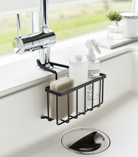 Side view of Yamazaki Home black Faucet-Hanging Sponge Caddy in a sink view 9