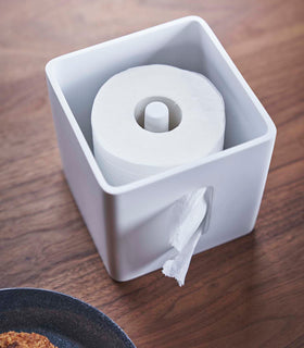 Aerial view of white toilet paper holder with cover off and holding toilet paper roll by Yamazaki Home. view 5