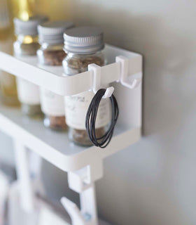 Close up side view of white Magnetic Organizer with Easy-Grip Rotating Clips hooks holding rubber bands by Yamazaki Home. view 5