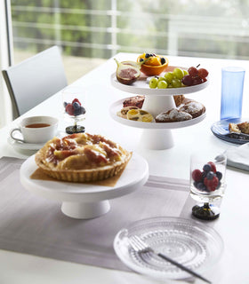 White Stackable Serving Stand displaying fruit and pastries on dining table by Yamazaki Home. view 4